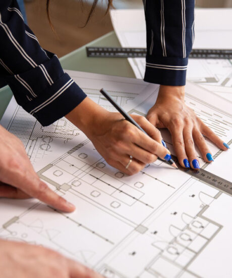 close-up-with-hands-two-architects-who-draw-something-house-plan-blueprints-new-construction-plan